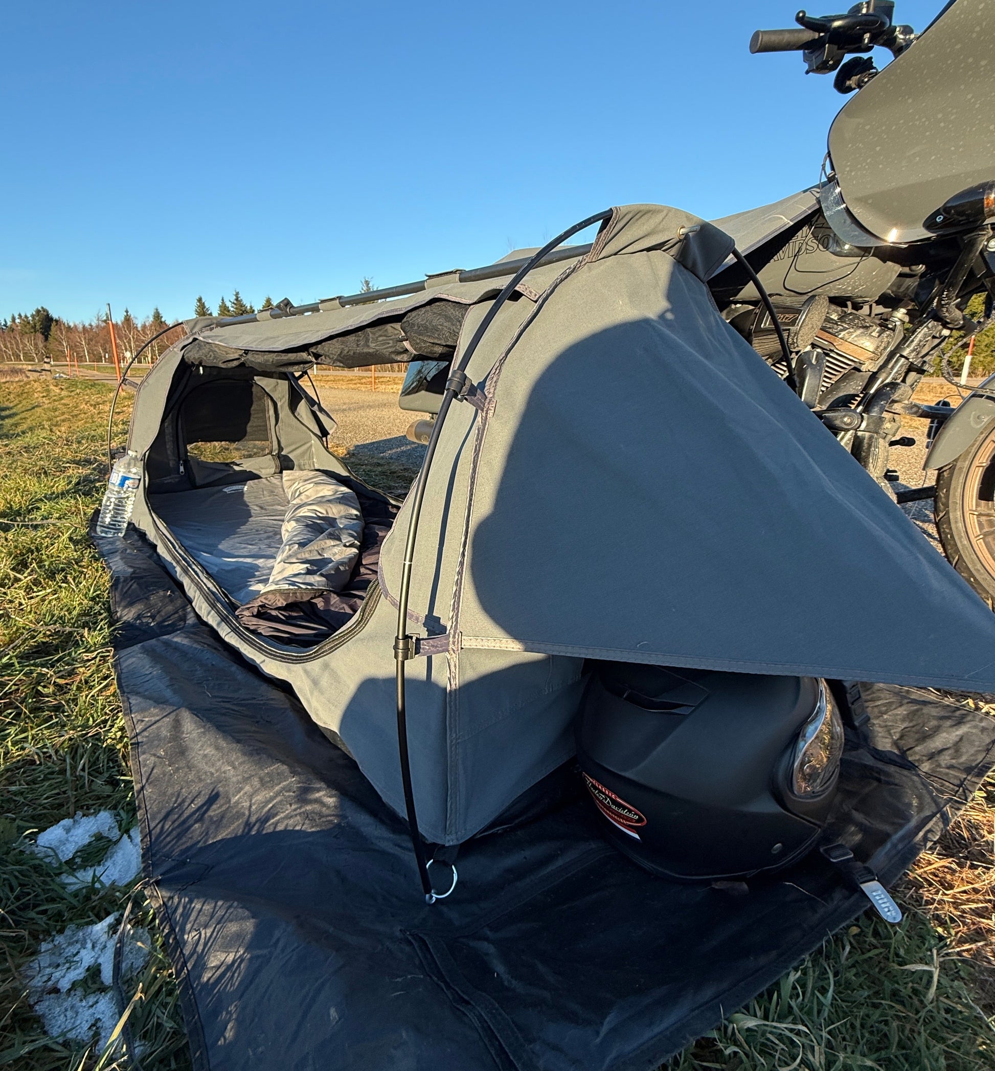 Motorcycle with a tent and helmet on a grassy field